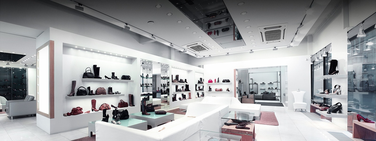 Two LG Multi V indoor units(idu) provide air conditioning in a modern, upscale retail store with white walls and sleek shelving displaying handbags and shoes.